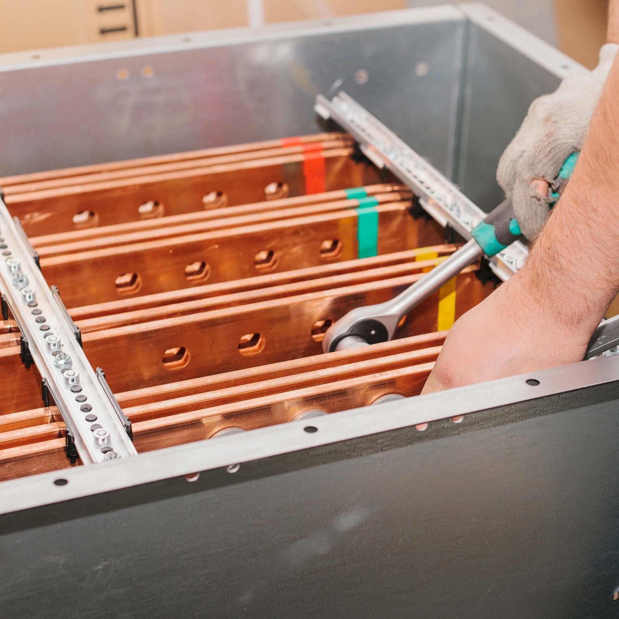 An ECS technician torques copper busbars into a switchgear chassis.